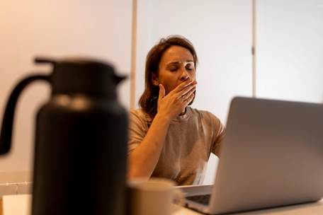 Mulher de 40 anos bocejando cansada em casa ou no escritório com laptop trabalhando tarde no escritório